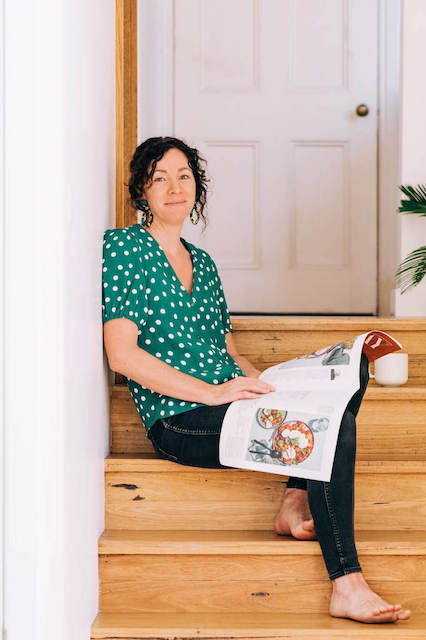 Lindy Alexander sits on steps and holds a magazine on her lap